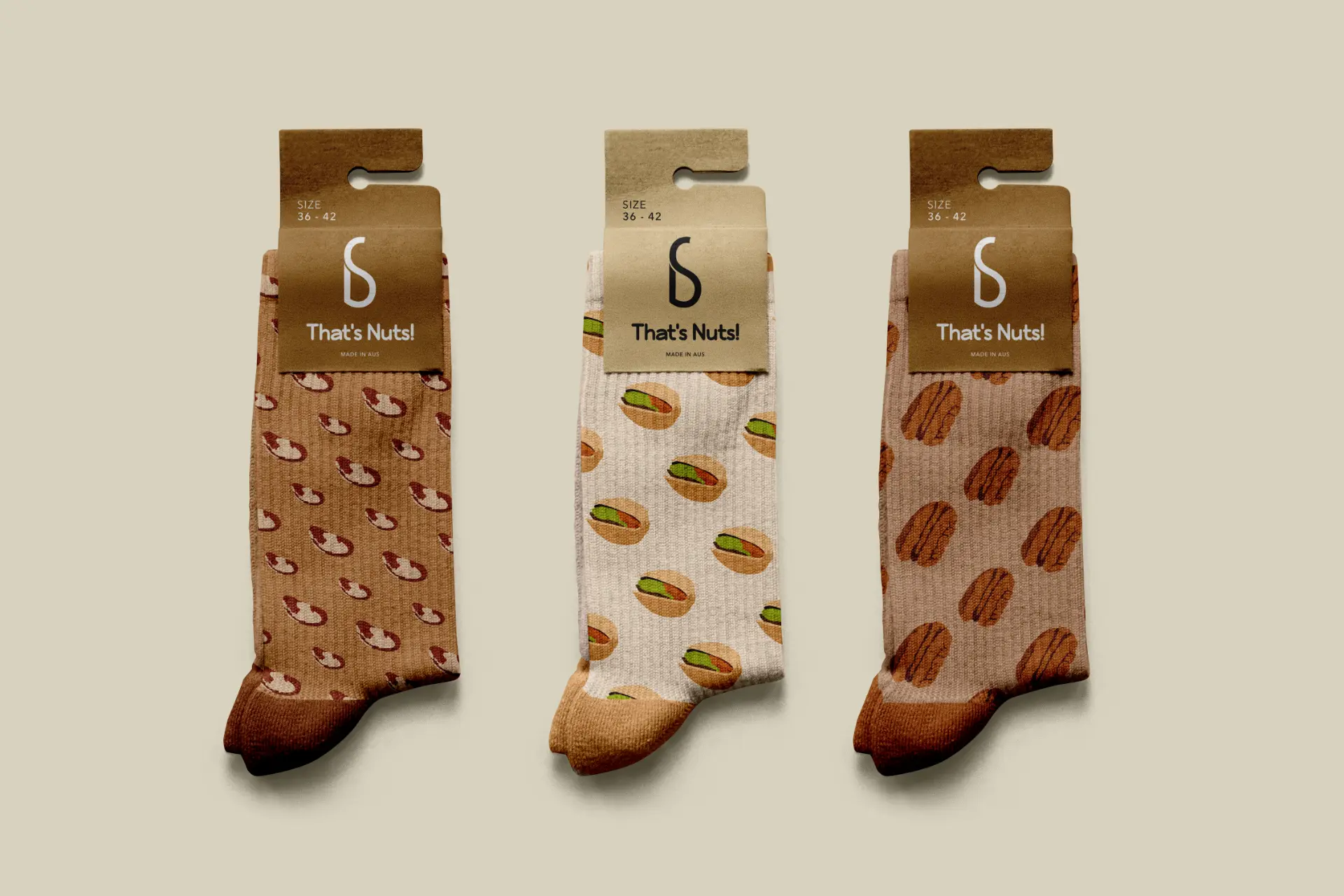 Three pairs of That's Nuts! socks with brazil nut, pistachio and pecan patterns in kraft packaging